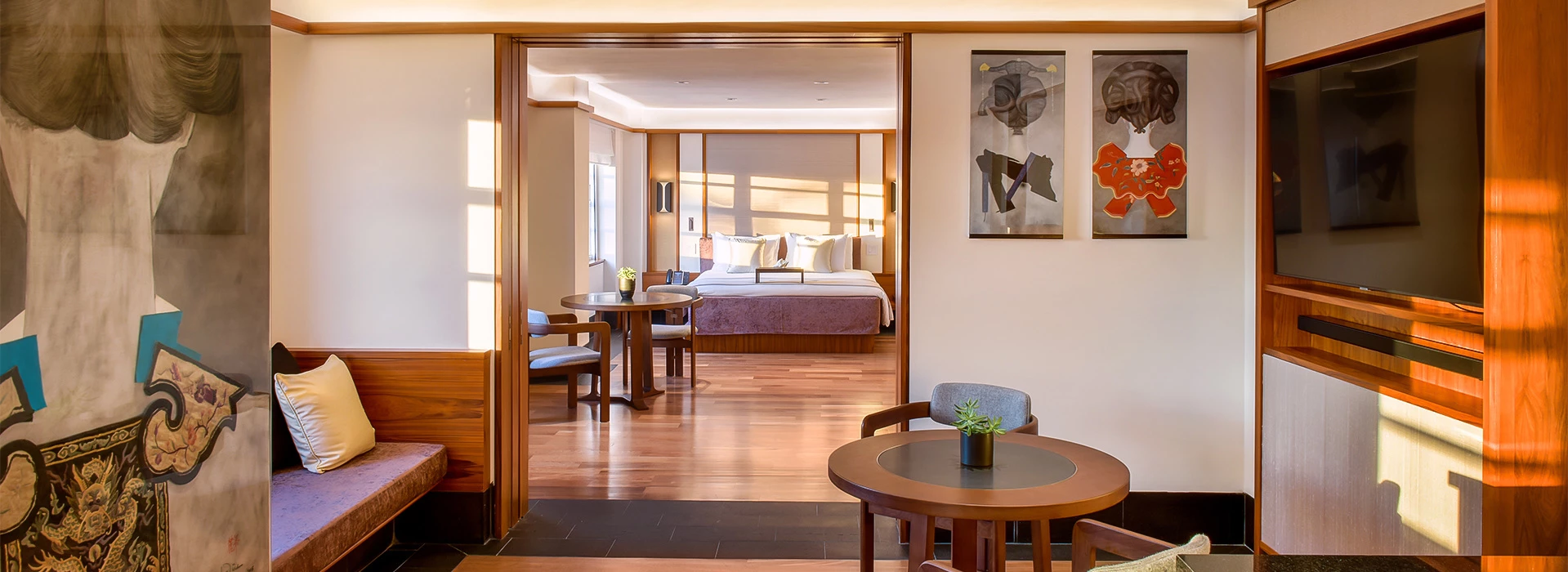A wide view of a hotel room with a sitting area and a bedroom in the background.