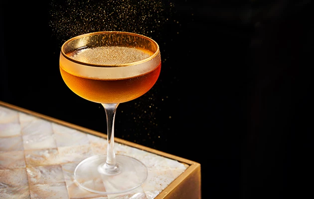 cocktail with gold shaving falling on top