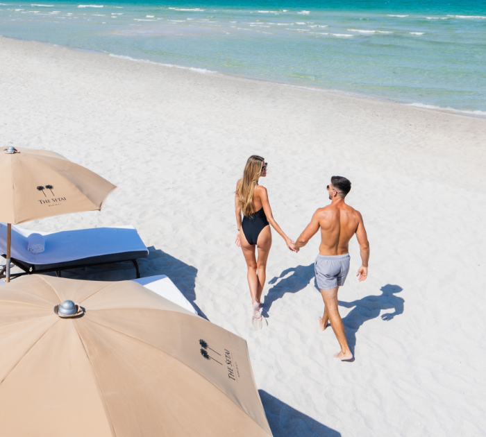 a man and woman holding hands on a beach