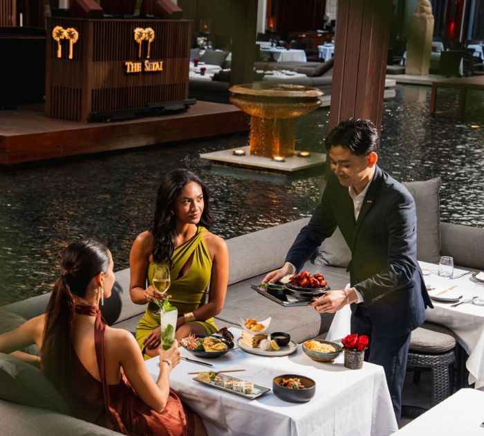 a group of people sitting at a table with food and drinks