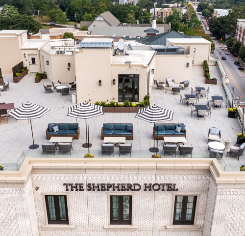 a rooftop of a hotel with chairs and umbrellas