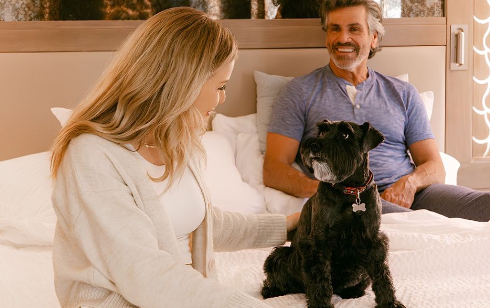 a man and woman sitting on a bed with a dog
