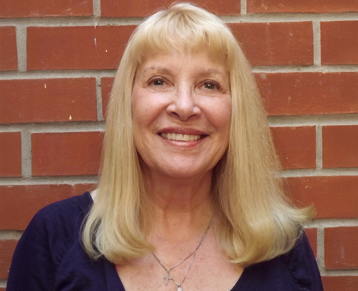a woman smiling in front of a brick wall