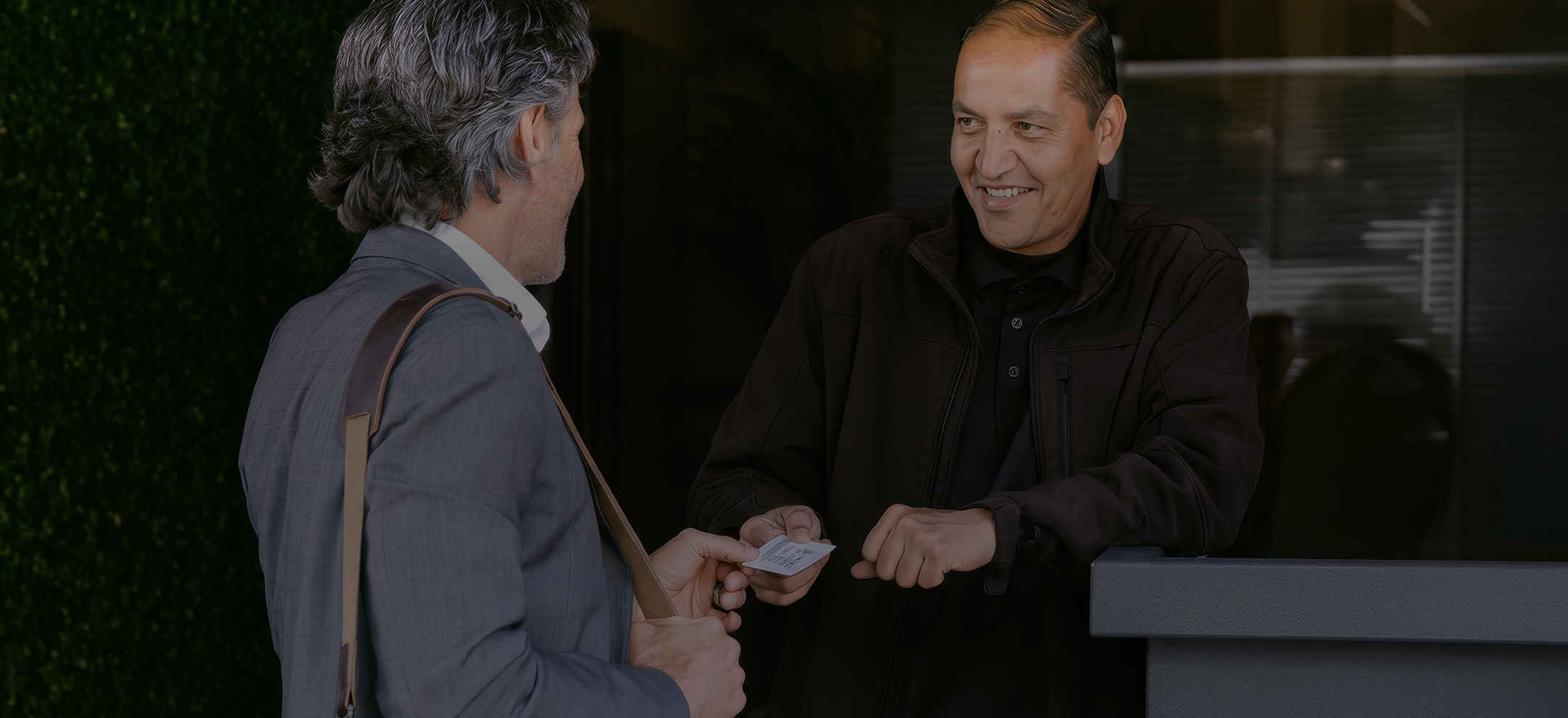 a man handing a card to another man