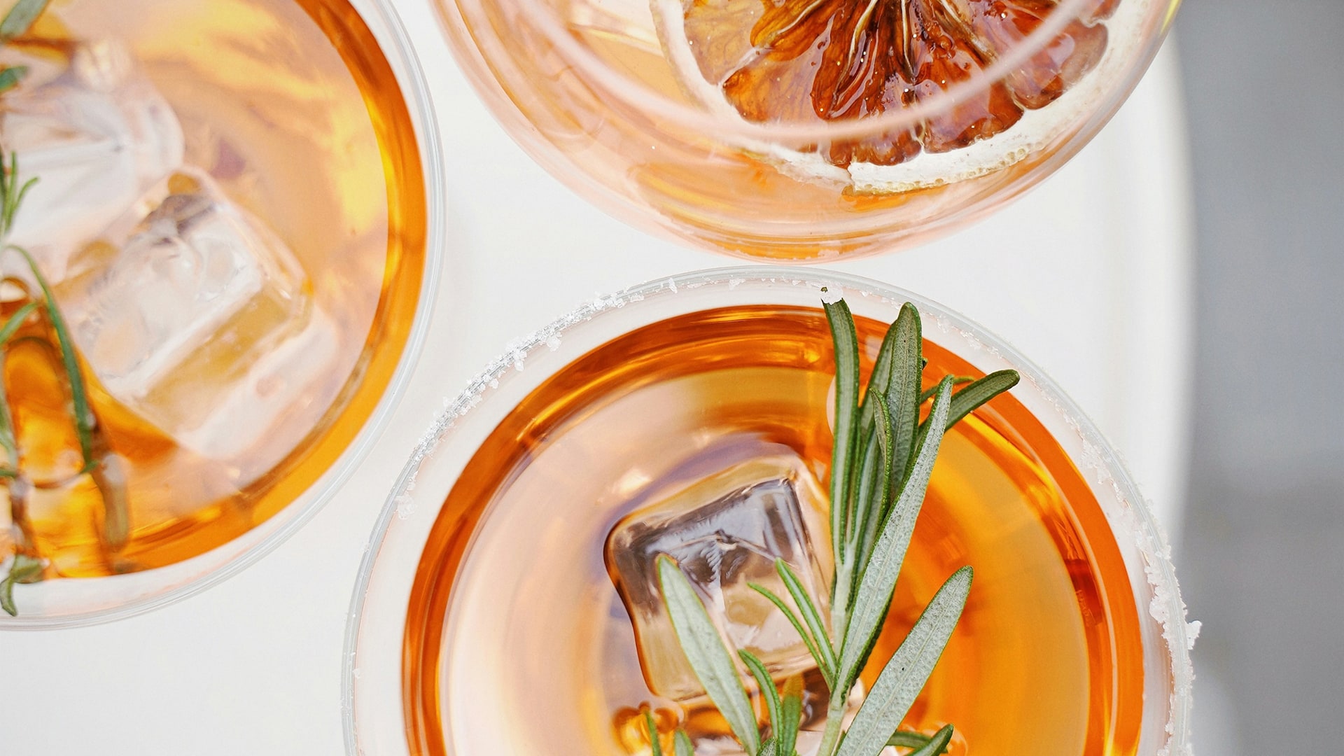 a group of glasses with liquid and a sprig of lemon