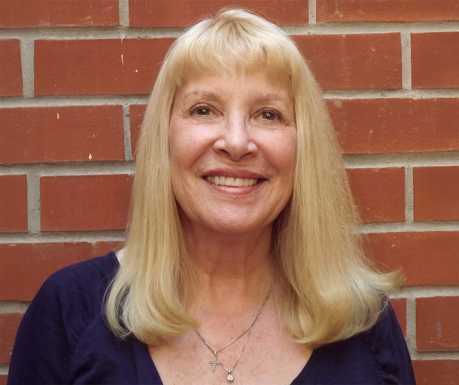 a woman smiling in front of a brick wall
