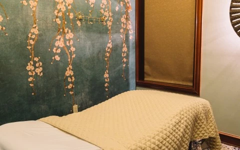a bed with a white blanket and a blue wall with flowers on it