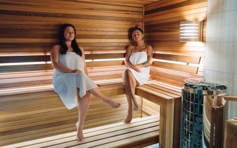 two women sitting on a bench in a sauna