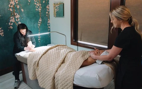 a woman lying on a bed with a woman in a room with a window