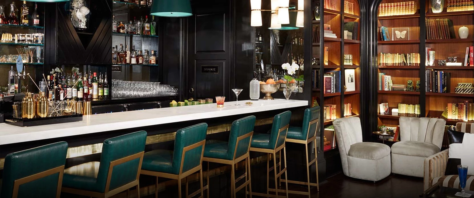 a bar with green chairs and a white counter