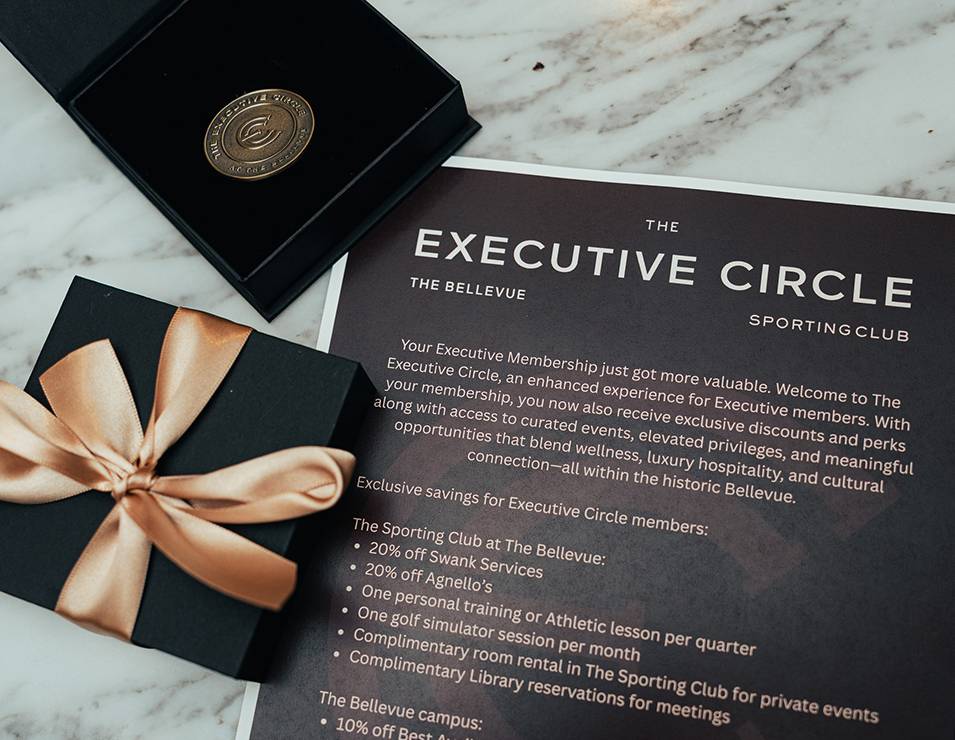 a black box with a gold ribbon and a gold coin in it next to a black box with a gold ribbon on it