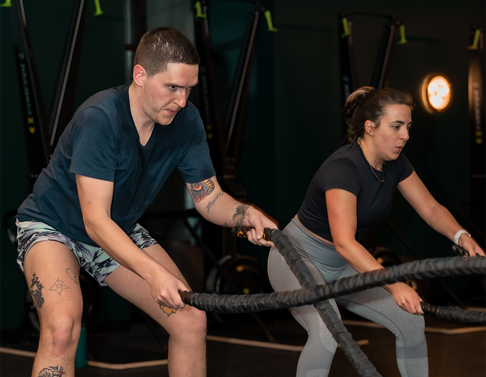 a man and woman working out with ropes