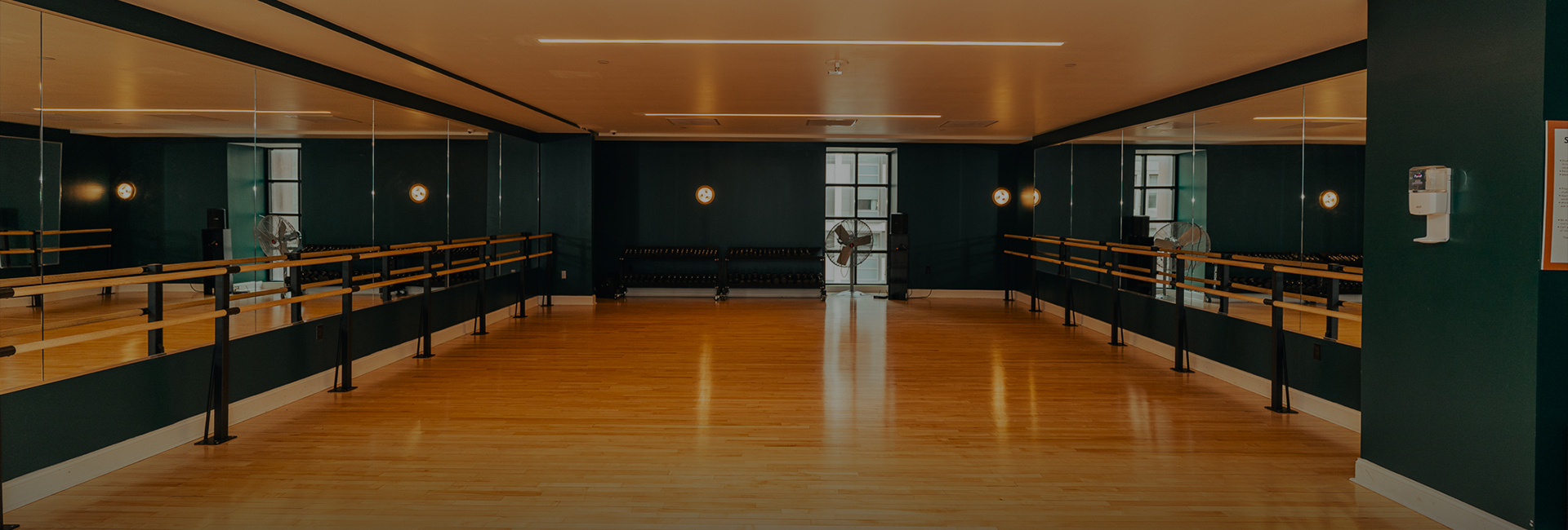 a dance studio with a wood floor and a fan