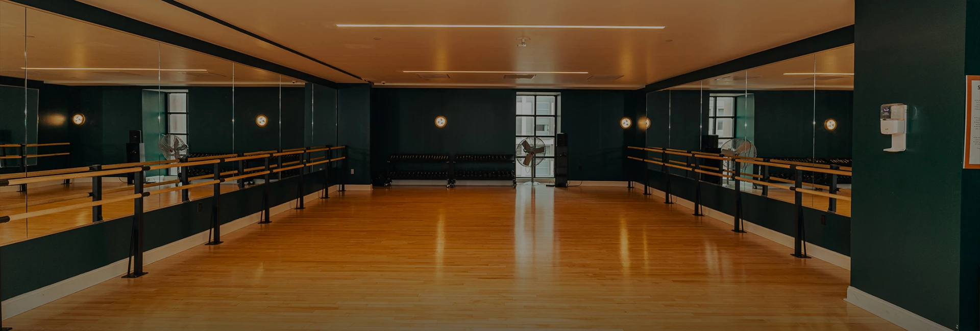 a dance studio with a wood floor and a fan