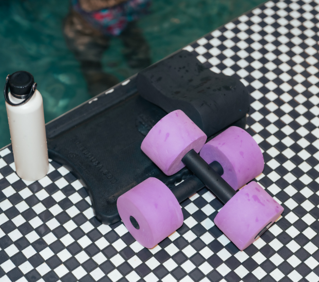 a pair of pink dumbbells on a black and white checkered surface