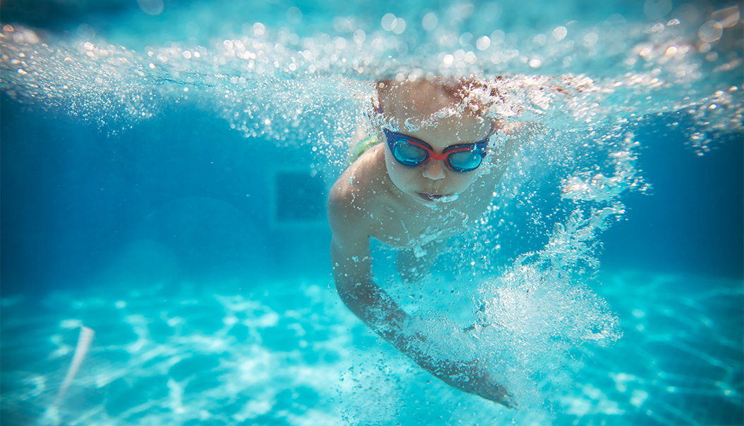 a child swimming underwater with goggles