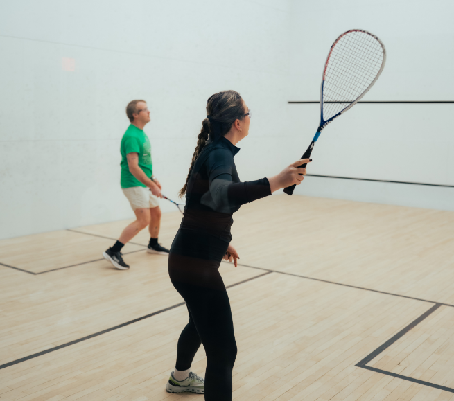 a woman holding a racket in a squash court