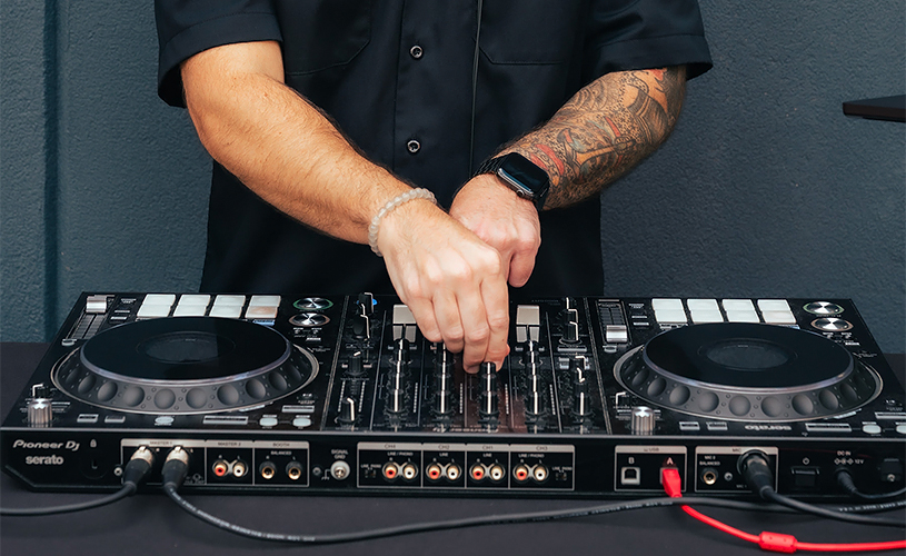 a person with tattoos on their arm and hands on a dj mixer