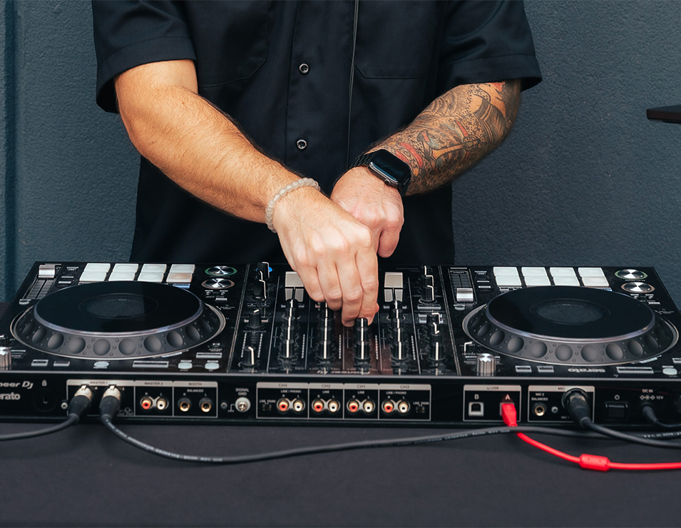 a person with tattoos on their arm and a dj mixer
