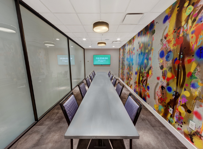 a long table and chairs in a room with a screen on the wall