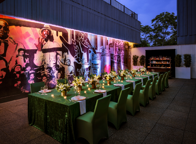 a long table set up with green chairs and flowers