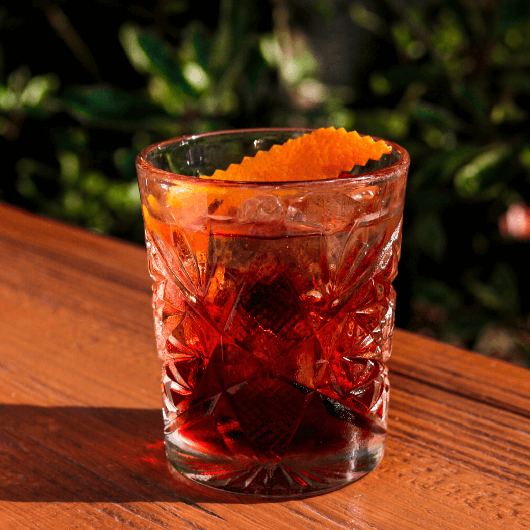 red cocktail with orange peel garnish