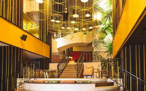 a staircase with a chandelier and a bench
