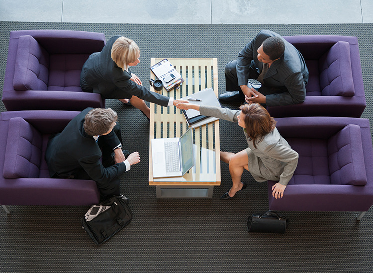 a group of people sitting around a table shaking hands