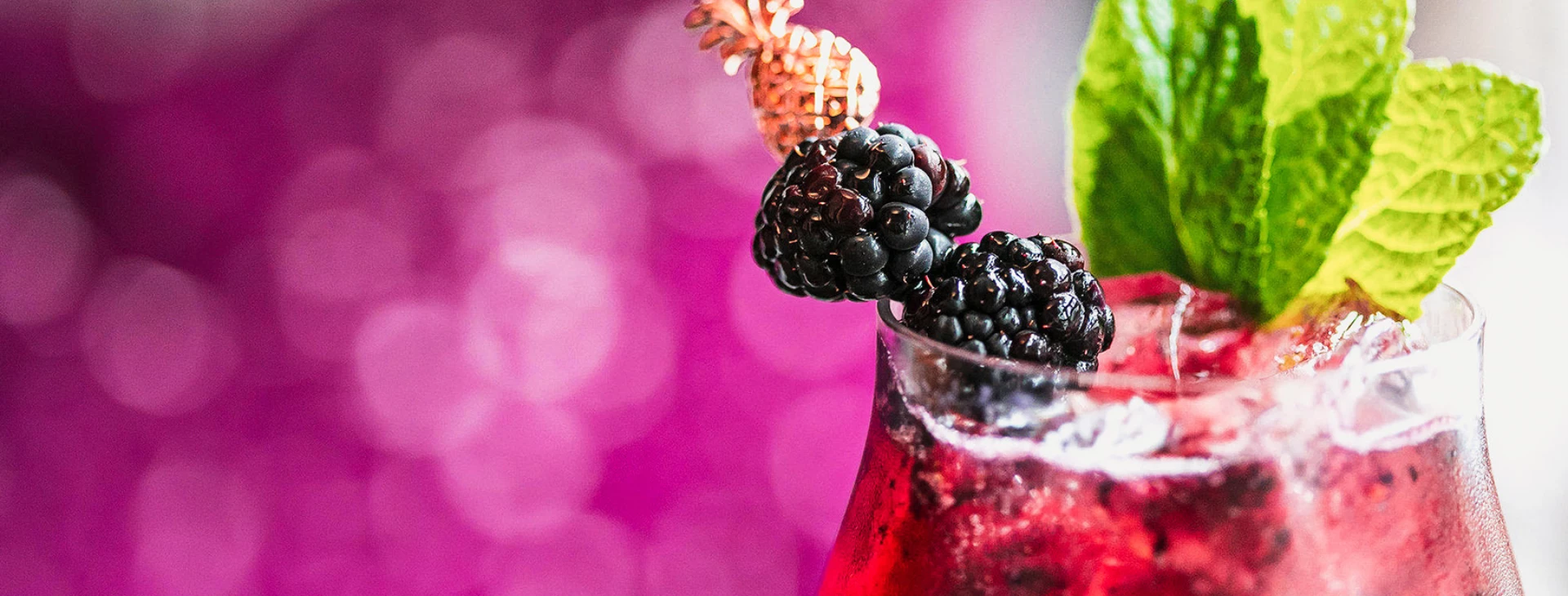 a red cocktail with blackberries in it and a flower in the middle