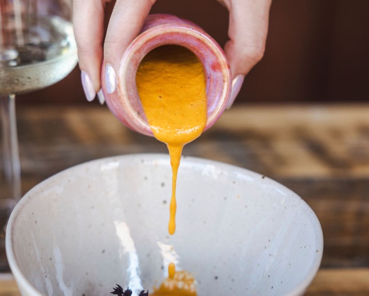 a hand pouring liquid into a bowl