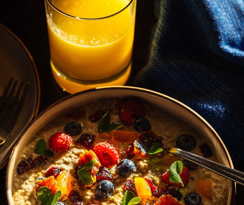 a bowl of oatmeal topped with berries and served with a glass of orange juice