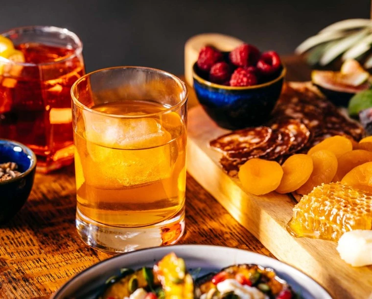 two cocktails next to charcuterie board