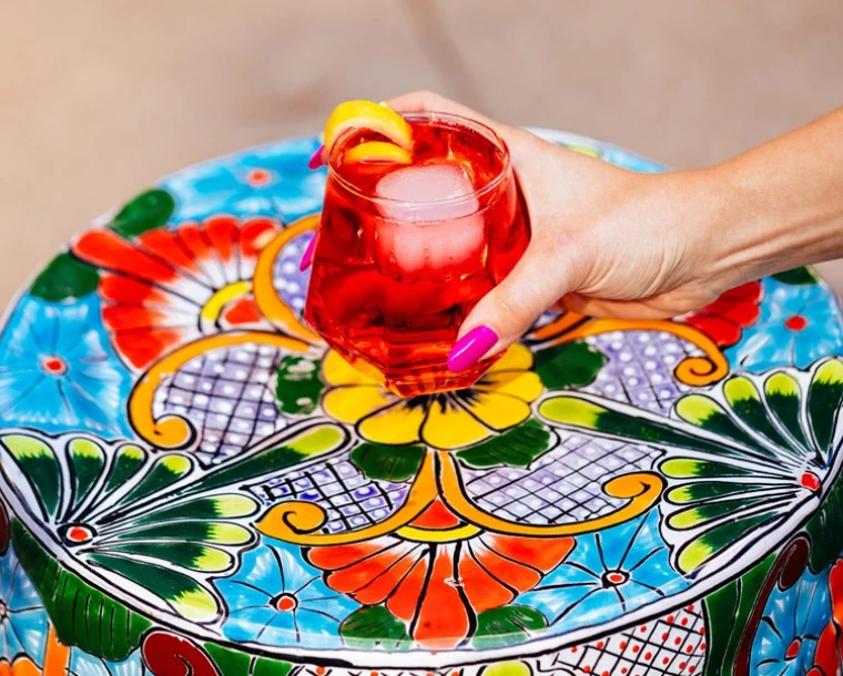 person holding cocktail over colorful table