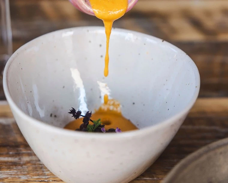 a bowl of food with a spoon pouring liquid into it