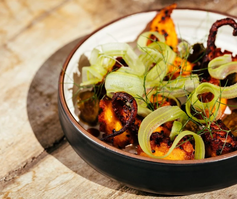 octopus dish with green garnishing in a bowl