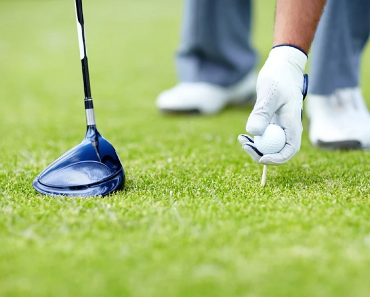 golfer putting his ball on the tee about to hit the ball