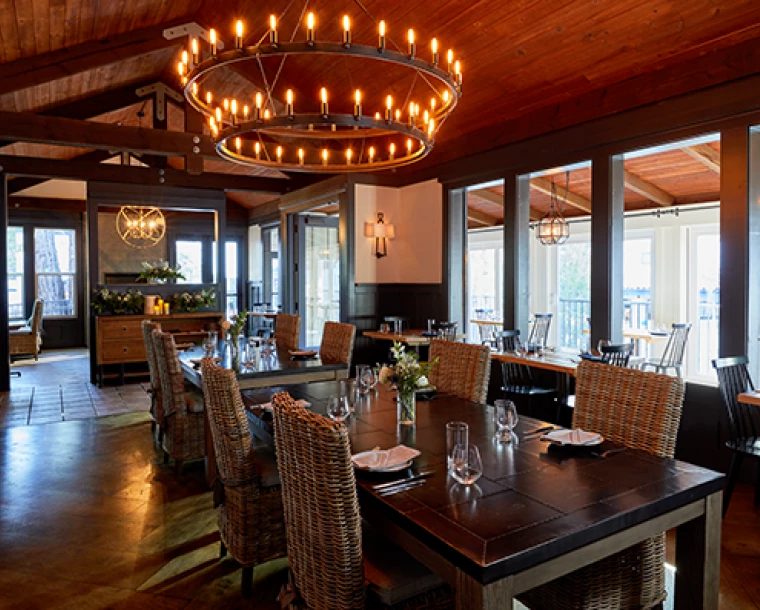 dining hall room covered in dark wood from floor to ceiling. Hanging above the restaurant tables is a large chandelier