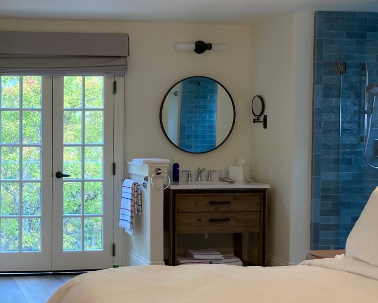 stavrand room with bed, sink and mirror, blue shower tiles and doors to the outside