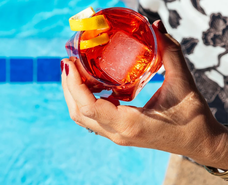 woman holding cocktail over the pool
