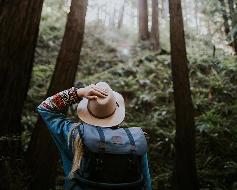 a woman in a hat wondering through a forest