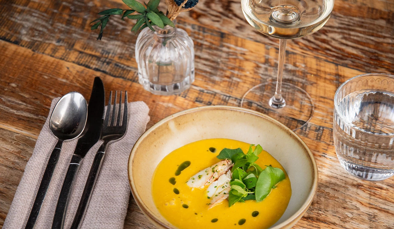 a bowl of soup with vegetables and a glass of wine
