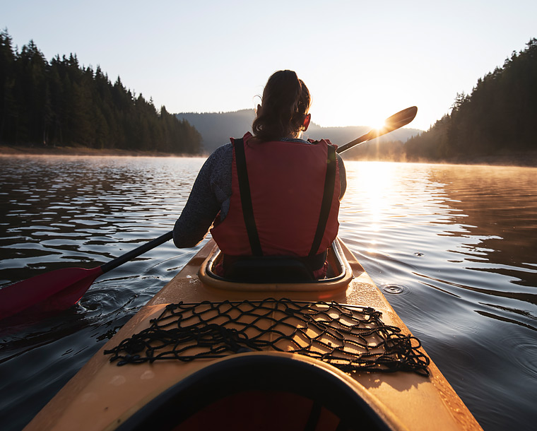 woman on a kayak looking into the sunset 