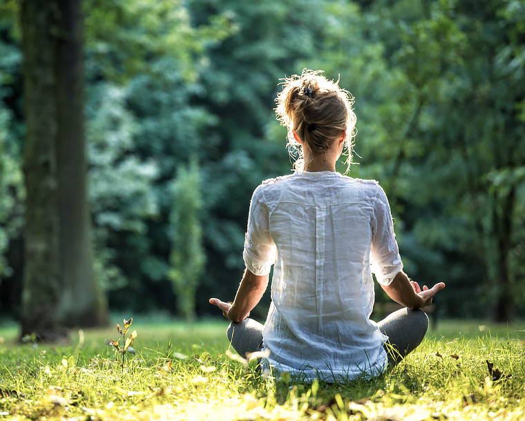 woman sitting on the grass in a yoga pose 