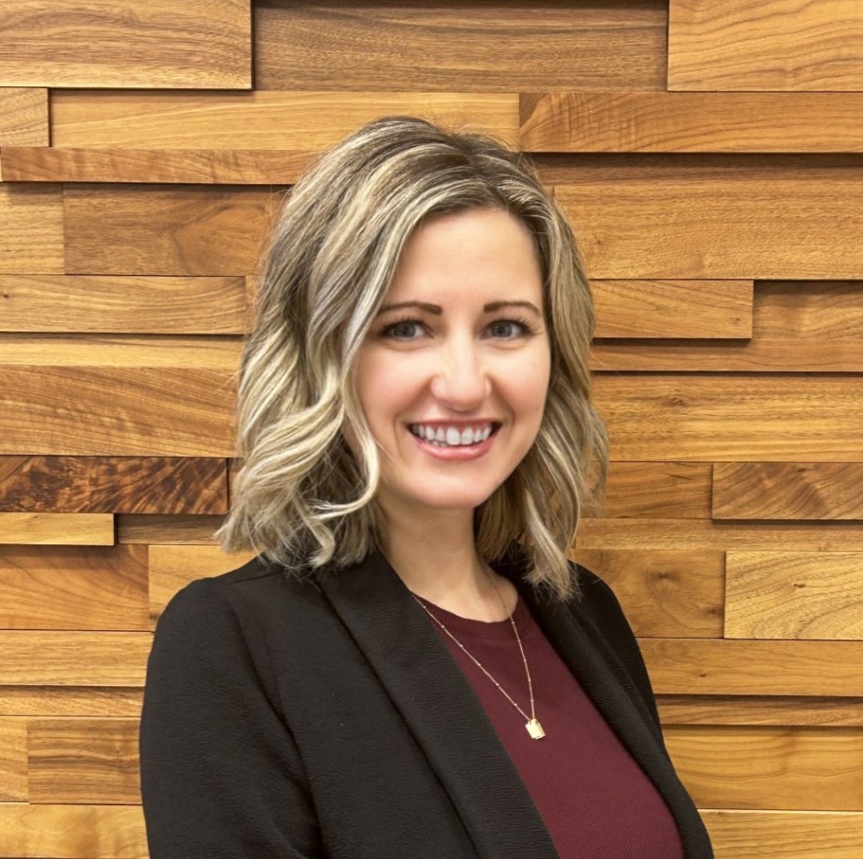a woman smiling in front of a wood wall
