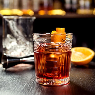 a nicely made cocktail in a highball glass with a orange peel