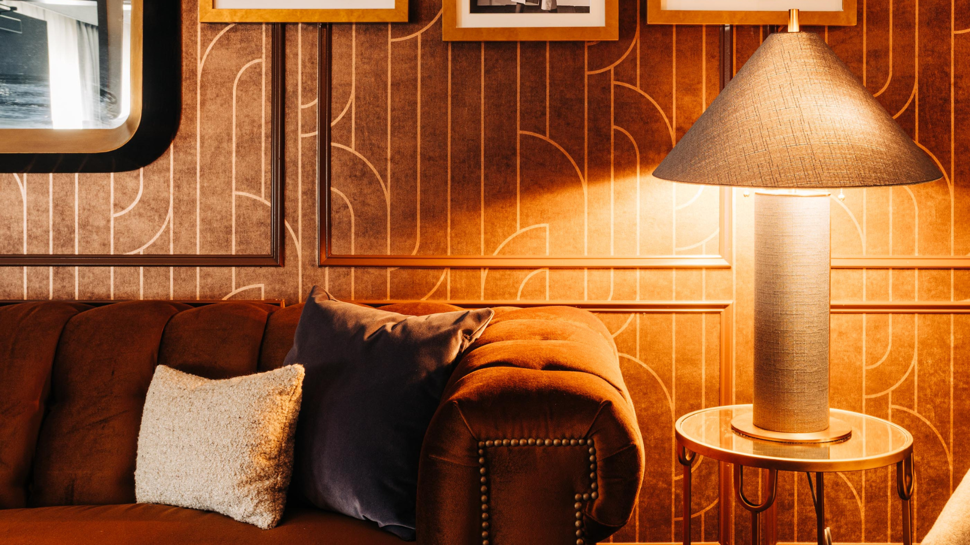 a couch with pillows and a lamp in front of a wall