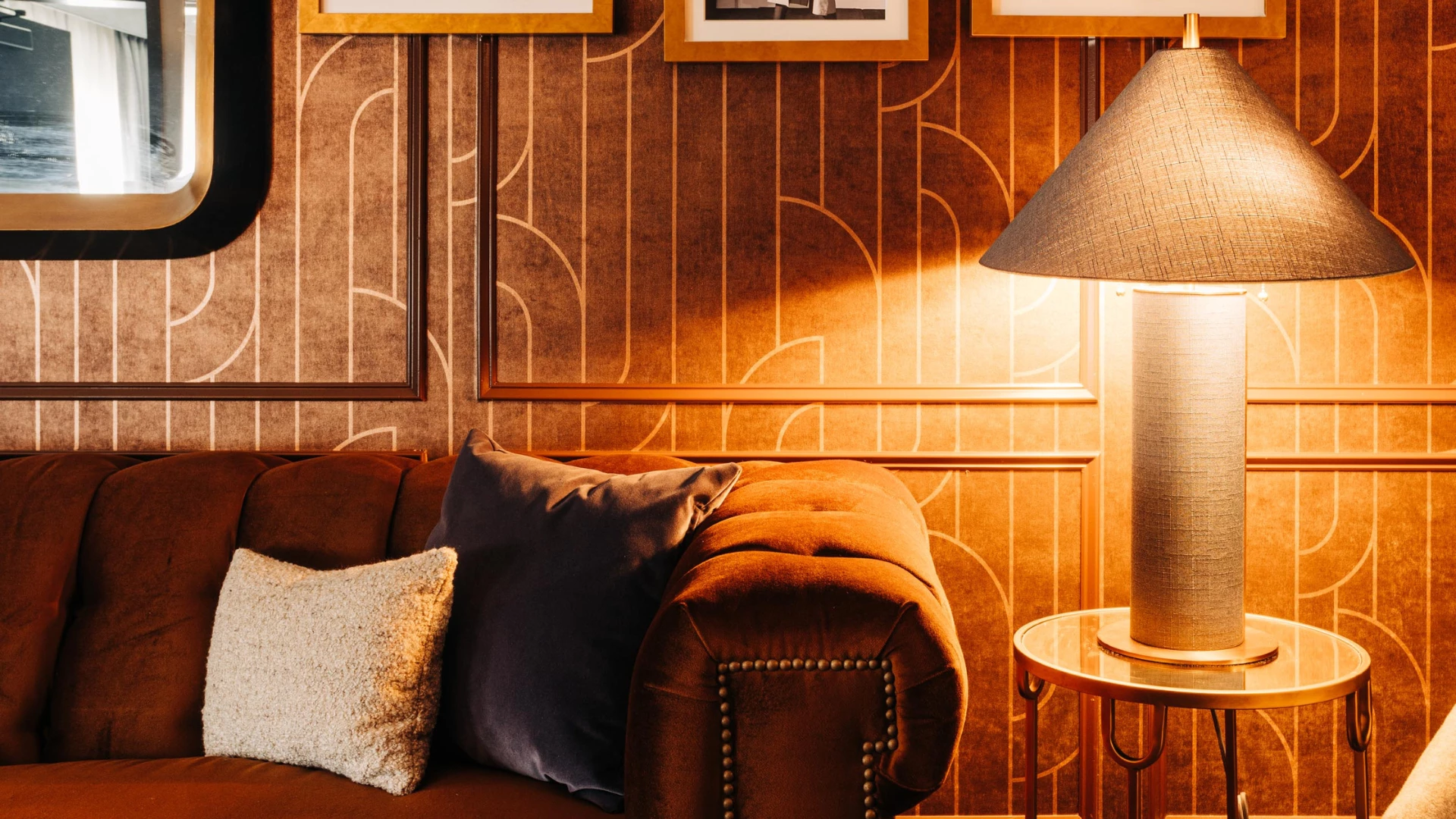 a couch with pillows and a lamp in front of a wall