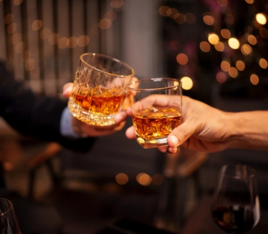 a close-up of two hands holding glasses with alcohol