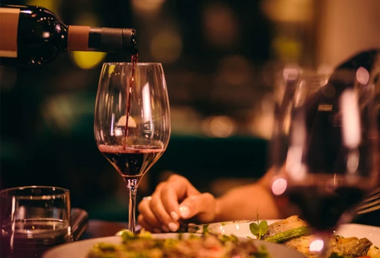 a person pouring wine into a glass
