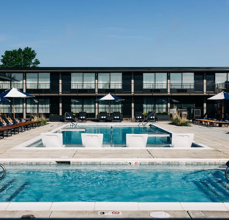 a pool with chairs and umbrellas in front of a building